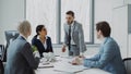 Businesswoman discussing reports with male and female colleagues sitting at the table in modern office Royalty Free Stock Photo