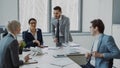 Businesswoman discussing reports with male and female colleagues sitting at the table in modern office Royalty Free Stock Photo