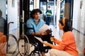 Businesswoman discussing with young businessman sitting in wheelchair at office corridor Royalty Free Stock Photo