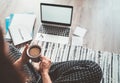 Businesswoman dressed in pajamas enjoying morning coffee on the floor office with laptop, papers top view shot. Distance