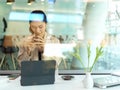 Businesswoman drinking coffee while working in workspace, view through glass view