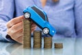 Businesswoman Driving Car On Declining Stacked Coins