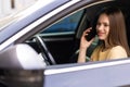 young woman driving car and talking on cell phone concentrating on the road