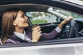 Businesswoman driving in a car to work during the day, drink coffee. Steering wheel on the right side of the car Royalty Free Stock Photo