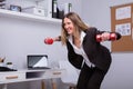 Businesswoman Exercising With Dumbbell In Office