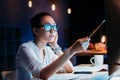 Businesswoman in eyeglasses holding pencil and working late in office Royalty Free Stock Photo