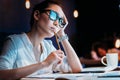 Businesswoman in eyeglasses holding pencil and working late in office Royalty Free Stock Photo