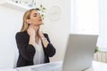 Businesswoman feeling pain in neck after sitting at the table with laptop. Tired female suffering of office syndrome because of Royalty Free Stock Photo