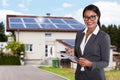 Businesswoman Filling Document In Front Of House