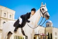Businesswoman fond of equestrianism hugging her white horse