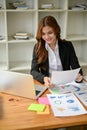 A businesswoman in a formal business suit is working on marketing reports at her desk Royalty Free Stock Photo