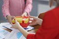 Businesswoman gives gift to colleague at workplace. Royalty Free Stock Photo