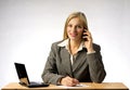 Businesswoman with gray jacket sitting at office tesk, talking on phone and writing a note with a pen on a paper. Royalty Free Stock Photo