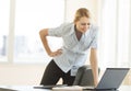 Businesswoman With Hand On Hip Looking At Laptop In Office Royalty Free Stock Photo