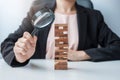 Businesswoman hand holding glass magnifying over wooden blocks tower. Business analysis, Risk Management, Study, opportunities and Royalty Free Stock Photo