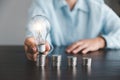 Businesswoman hand holding lightbulb with stack coins. Idea of saving energy and accounting finance in home and family, save world Royalty Free Stock Photo