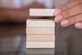 Businesswoman Hand Placing Wooden Block On Wooden Tower