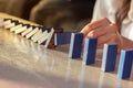 Businesswoman hand trying to stop toppling dominoes on table