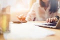 Businesswoman hand working laptop and use calculator on wooden desk in office in morning light.