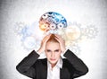 Businesswoman with hands on head, gears and colourful brain sketch on grey wall Royalty Free Stock Photo