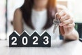 Businesswoman hands holding key and 2023 Happy New Year with house model on table office. New House, Financial, Property insurance Royalty Free Stock Photo