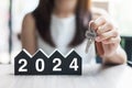 Businesswoman hands holding key and 2024 Happy New Year with house model on table office. New House, Financial, Property insurance Royalty Free Stock Photo