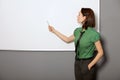 Businesswoman with hands in pockets pointing at whiteboard in office Royalty Free Stock Photo