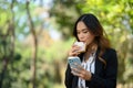 Businesswoman having lunch break eating sandwich and using mobile phone in the park Royalty Free Stock Photo