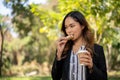 A businesswoman is having a quick breakfast in a city park, eating a sandwich and drinking coffee Royalty Free Stock Photo