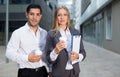 Businesswoman and her partner are standing with folder and coffee