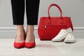 Businesswoman in high heel shoes standing near comfortable sneakers and bag indoors, closeup Royalty Free Stock Photo