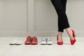 Businesswoman in high heel shoes standing near different comfortable sneakers indoors, closeup Royalty Free Stock Photo