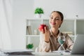 Businesswoman holding apple at workplace with sand clock and laptop in office Royalty Free Stock Photo