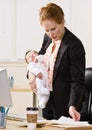 Businesswoman holding baby at desk