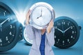 Composite image of businesswoman holding clock in front of face