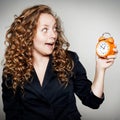 Businesswoman holding clock in hands. Deadline concept with shocked woman holding alarm clock.