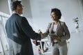 Businesswoman holding digital tablet and looking at handsome colleague while shaking hands in office Royalty Free Stock Photo