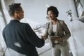 Businesswoman holding digital tablet and looking at handsome colleague while shaking hands in office Royalty Free Stock Photo