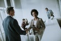 Businesswoman holding digital tablet and looking at handsome colleague while shaking hands in office Royalty Free Stock Photo