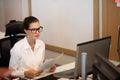 Businesswoman holding documets while looking at laptop