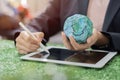 Businesswoman holding an Earth model and use tablet for analyze Environmental technology and approaching global sustainable ESG