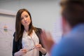 Businesswoman Holding Eyeglasses While Looking At Colleague