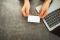 A businesswoman holding and giving a blank business cards while using laptop computer in office Royalty Free Stock Photo