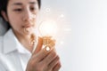 Businesswoman holding glowing light bulb, with eco-friendly energy resources icon