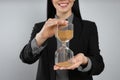 Businesswoman holding hourglass on light grey background, closeup. Time management Royalty Free Stock Photo