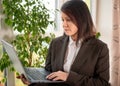 Businesswoman holding laptop. adult woman wearing suit holding silver laptop in office on window background. Adult woman holding Royalty Free Stock Photo