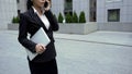 Businesswoman holding laptop and talking on cellphone, personal assistant to CEO Royalty Free Stock Photo