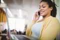 Businesswoman holding laptop while using mobile phone in office cafeteria Royalty Free Stock Photo