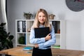 Businesswoman Holding Large File. young womanl standing in the office and holding folder. Portrait of young office worker holding Royalty Free Stock Photo