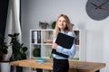 Businesswoman Holding Large File. young womanl standing in the office and holding folder. Portrait of young office worker holding Royalty Free Stock Photo